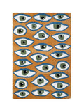 Alfombra rectangular Amuleto con patrón de ojos en colores azul, verde y blanco sobre fondo color mostaza.