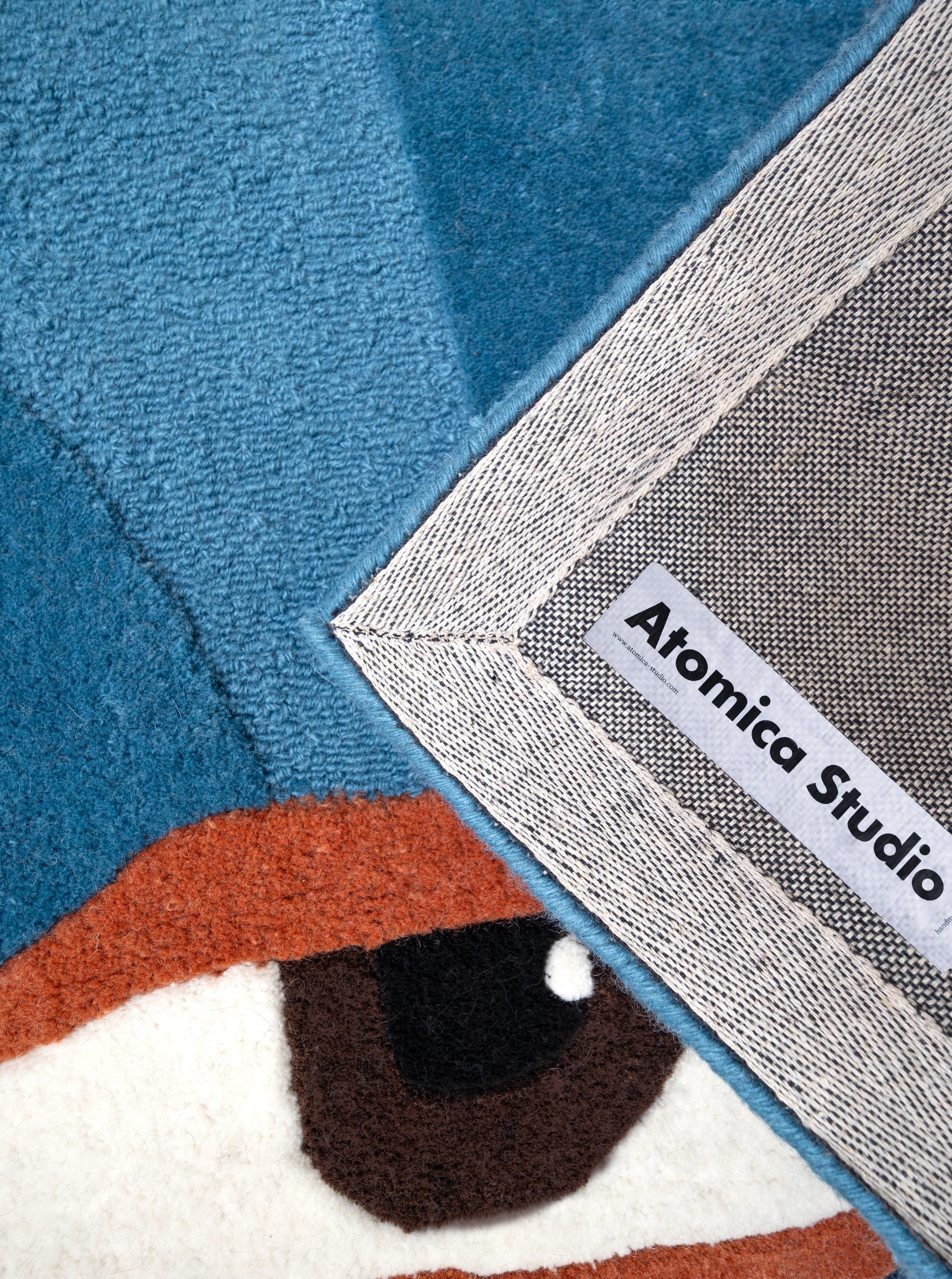 Detalle del reverso de la alfombra Talismán mostrando la etiqueta de Estefanía Franco y el acabado reforzado del borde.