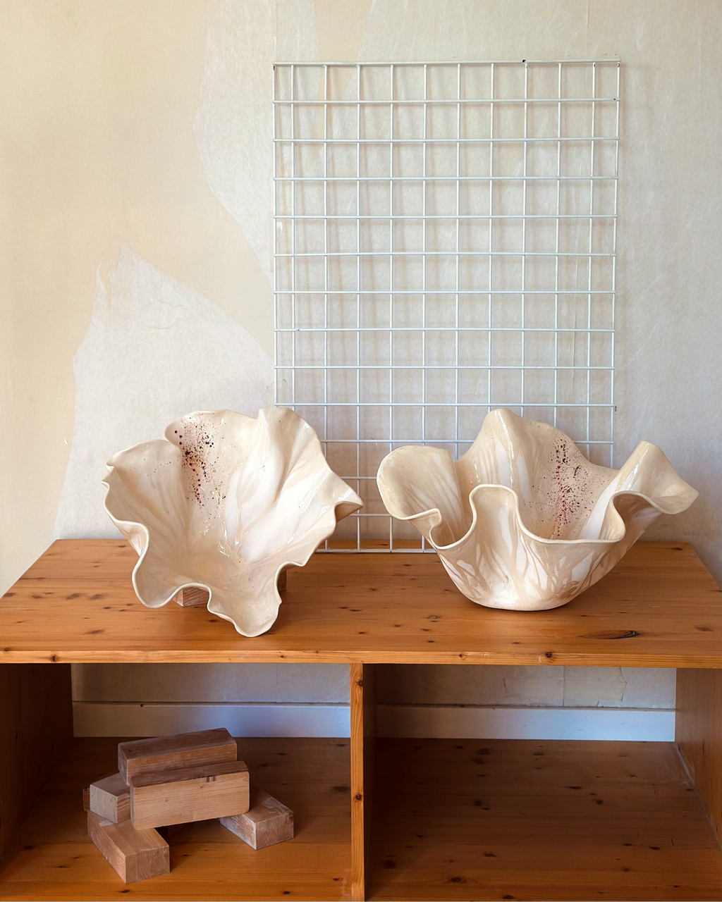Pareja de piezas Flor Calima de artesanía contemporánea; fuentes de cerámica de autor con morfología orgánica y esmaltes de alta temperatura en una estantería de madera.