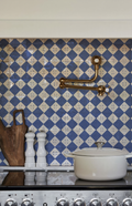 Ambiente de cocina de alta gama con grifería pot filler de cobre, olla de hierro fundido y el Azulejo Diamante en bruto con patrón geométrico azul instalado en el frente de cocción.