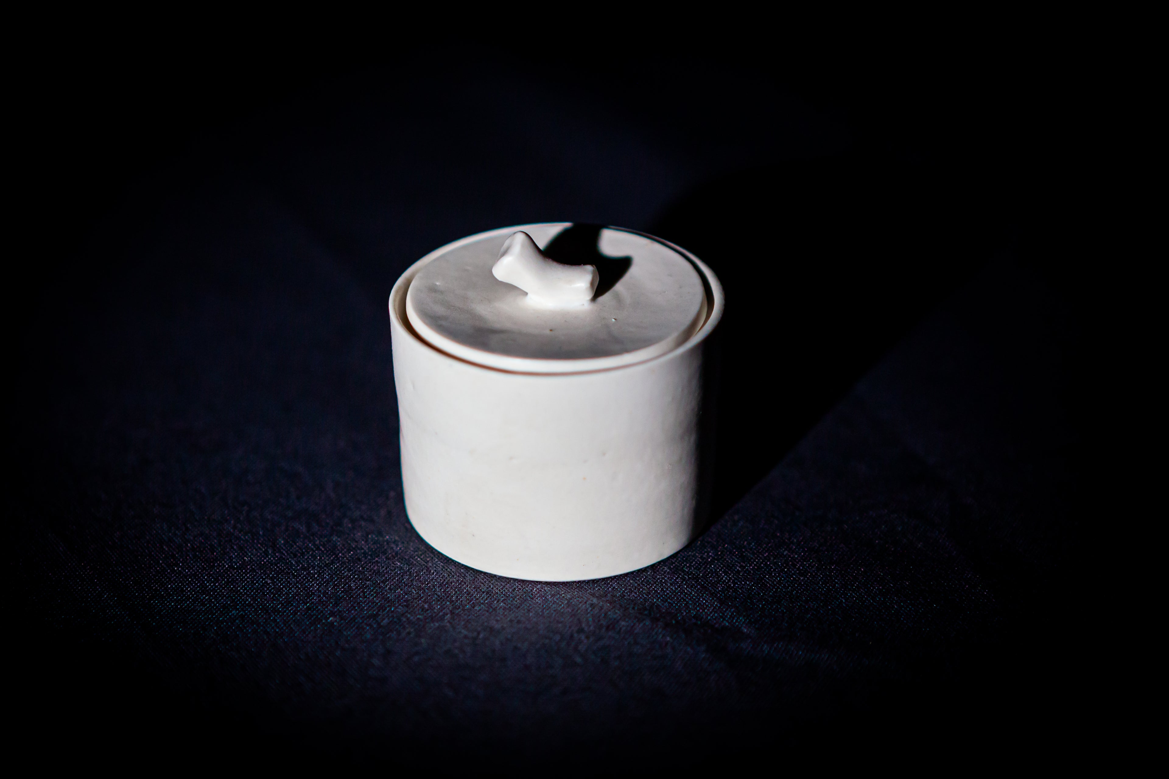 Caja cuadrada de porcelana blanca artesanal con tapa, de líneas minimalistas y bordes suaves.