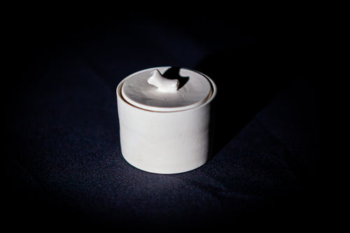Caja cuadrada de porcelana blanca artesanal con tapa, de líneas minimalistas y bordes suaves.