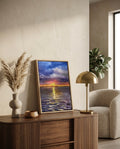 Primer plano de la pintura al óleo de atardecer, "Destellos en el mar", enmarcada en madera natural y colocada sobre un aparador moderno de listones junto a una lámpara dorada y pampas grass, reflejando el estilo de Sezme Decor.