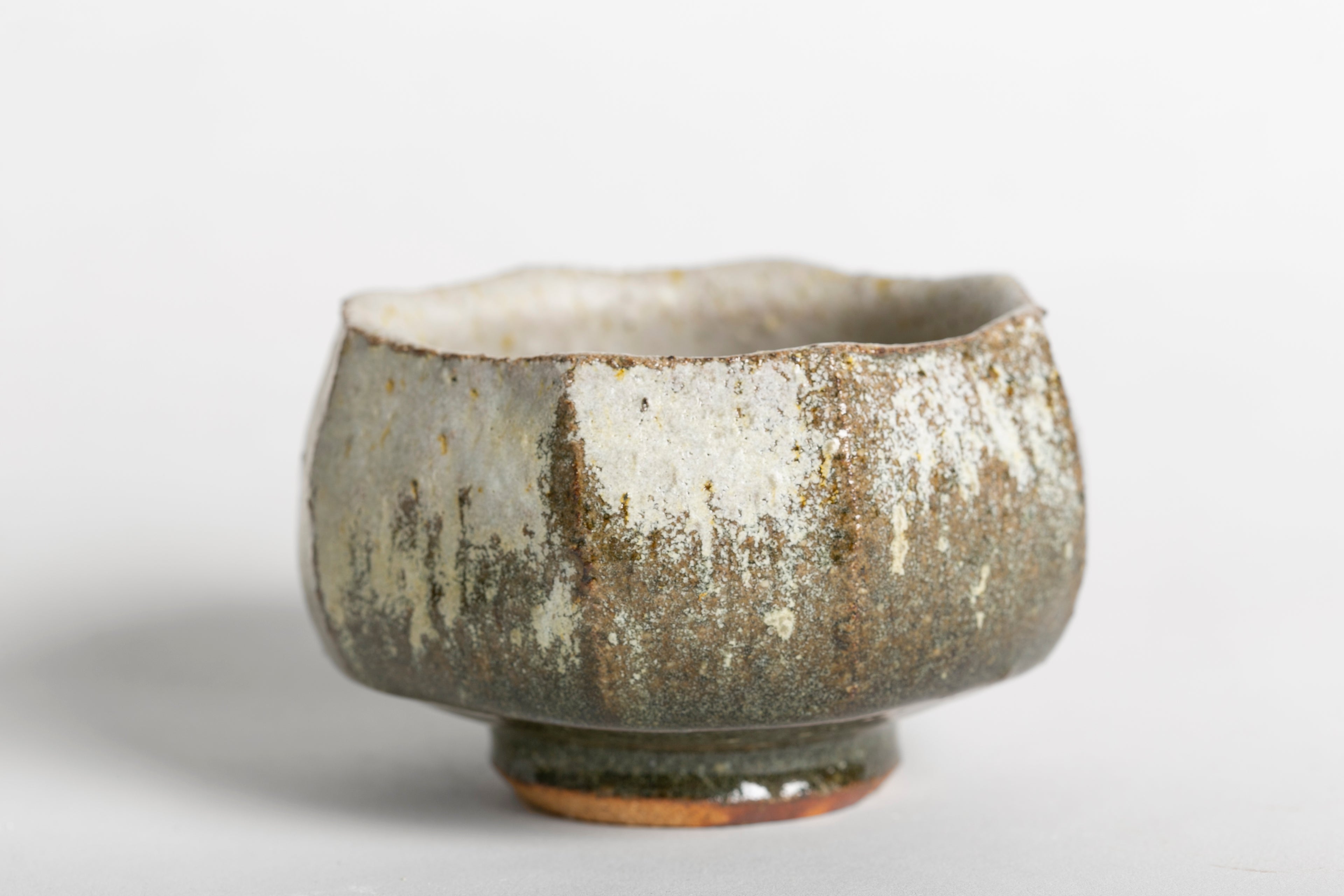 Cuenco artesanal con textura exterior rugosa y matices en tonos tierra y gris.