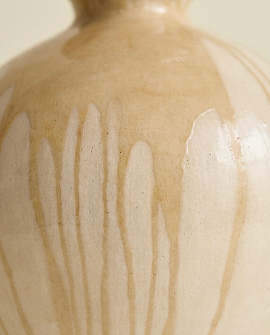 Primer plano macro del acabado esmaltado fluido con efecto de goteo en tonos crema de la escultura de diseño Calima Sfera de Cecilia Behrend.