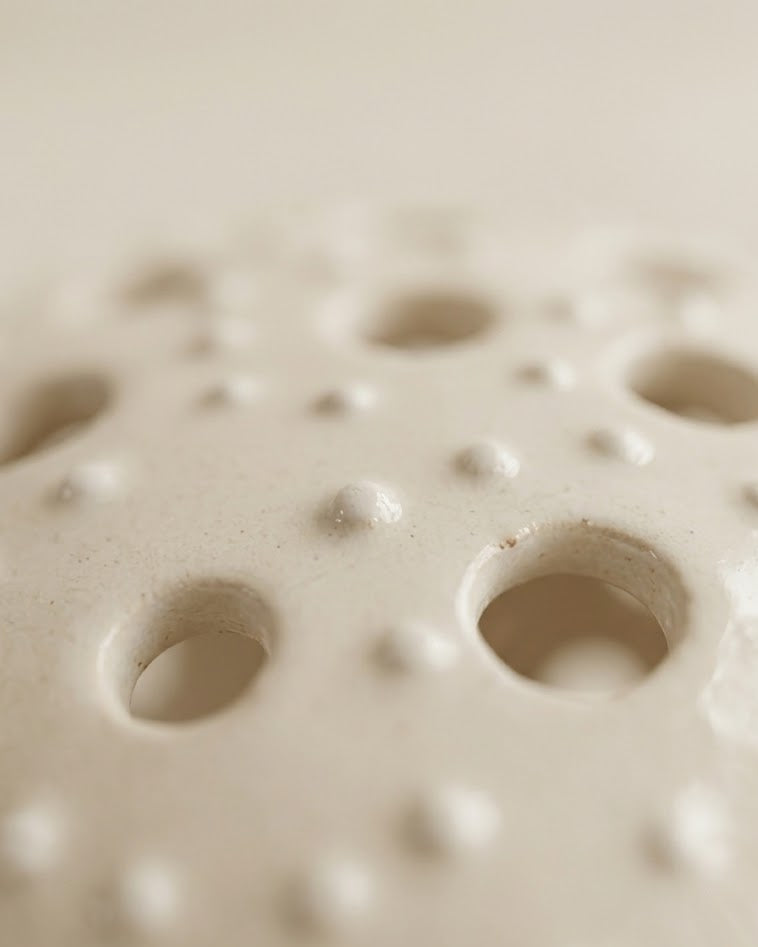 Primer plano macro de la textura de puntos en relieve y el acabado esmaltado brillante de un portavelas de gres hecho a mano.