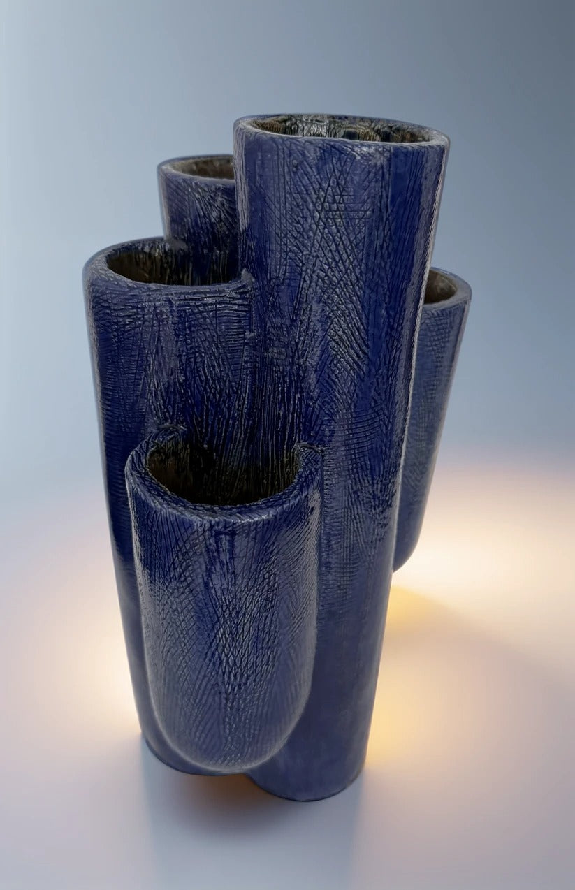 Plano medio que destaca la textura rayada artesanal y el brillo del esmalte azul cobalto bajo la luz.