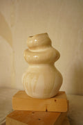 Pequeña escultura de cerámica Calima Little con niveles bulbosos y detalle de esmalte crema goteado sobre fondo neutro.
