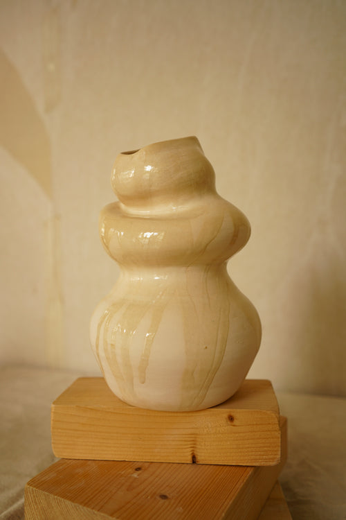 Pequeña escultura de cerámica Calima Little con niveles bulbosos y detalle de esmalte crema goteado sobre fondo neutro.