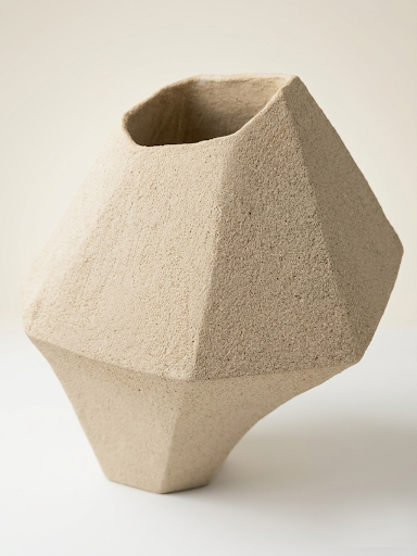 Primer plano de la base y el cuerpo inferior de la escultura "ÁRIDO", destacando la porosidad del gres y los pliegues orgánicos que simulan la erosión de una roca sedimentaria.
