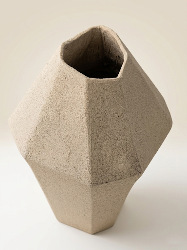 Plano picado de la escultura "ÁRIDO" de Fernanda Salomé, mostrando la apertura superior y la distribución de sus volúmenes orgánicos en gres beige sobre un fondo crema claro.