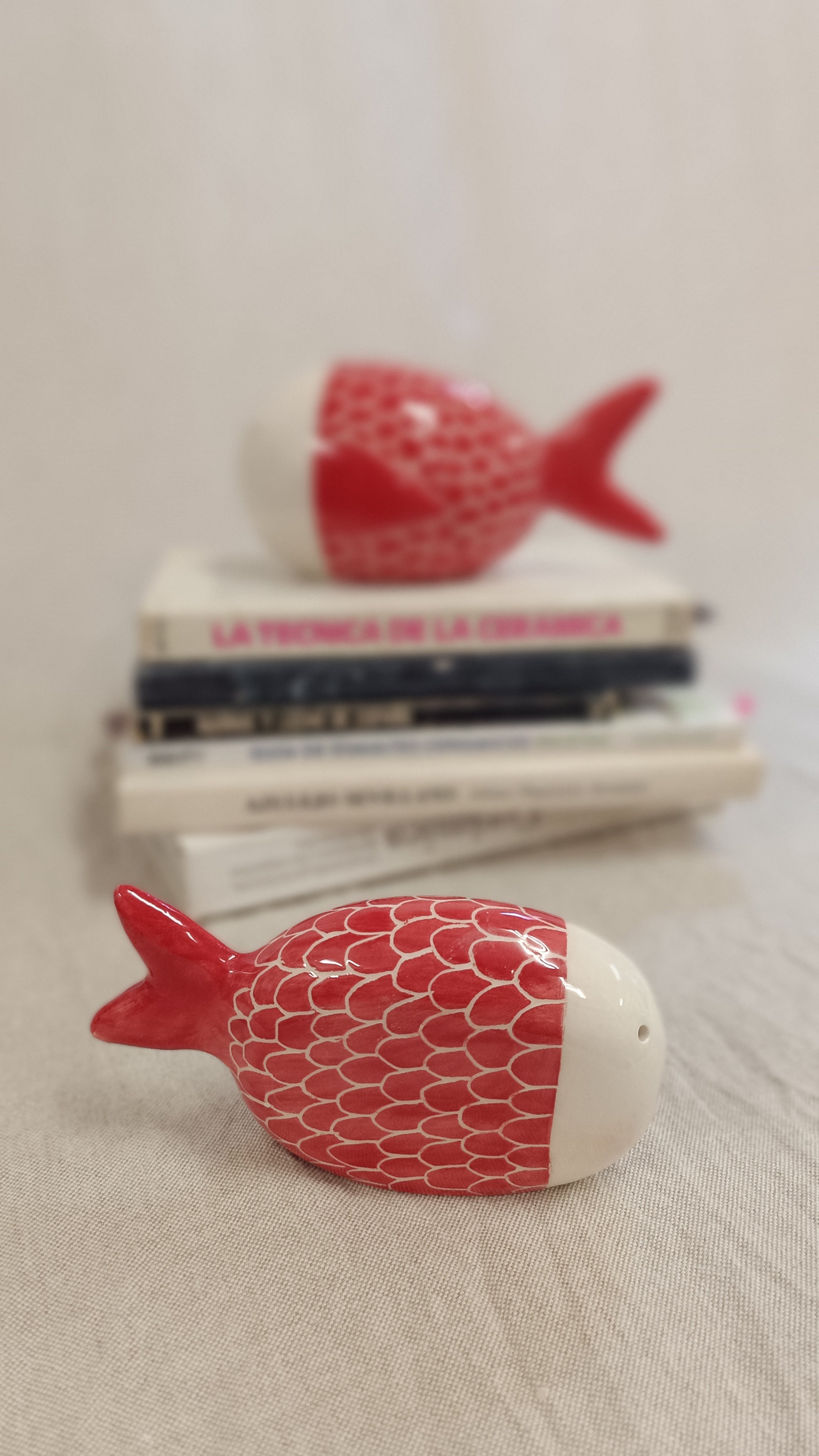 Escultura de pez de Vicente Rivera presentada sobre libros de técnica cerámica, resaltando su valor como pieza de arte de colección.