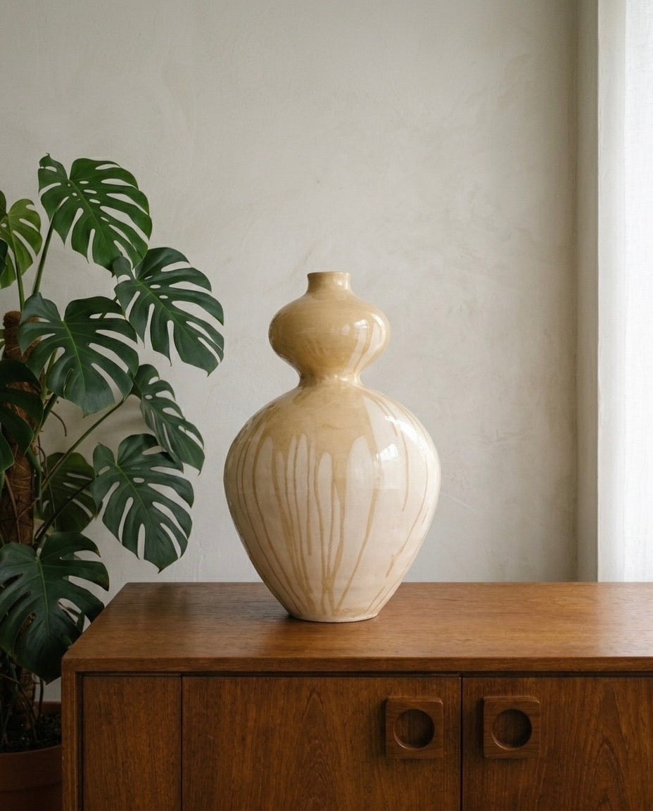 Escultura de cerámica Sfera de Cecilia Behrend para Sezme Decor, sobre un aparador de madera oscura en un ambiente minimalista junto a una planta.