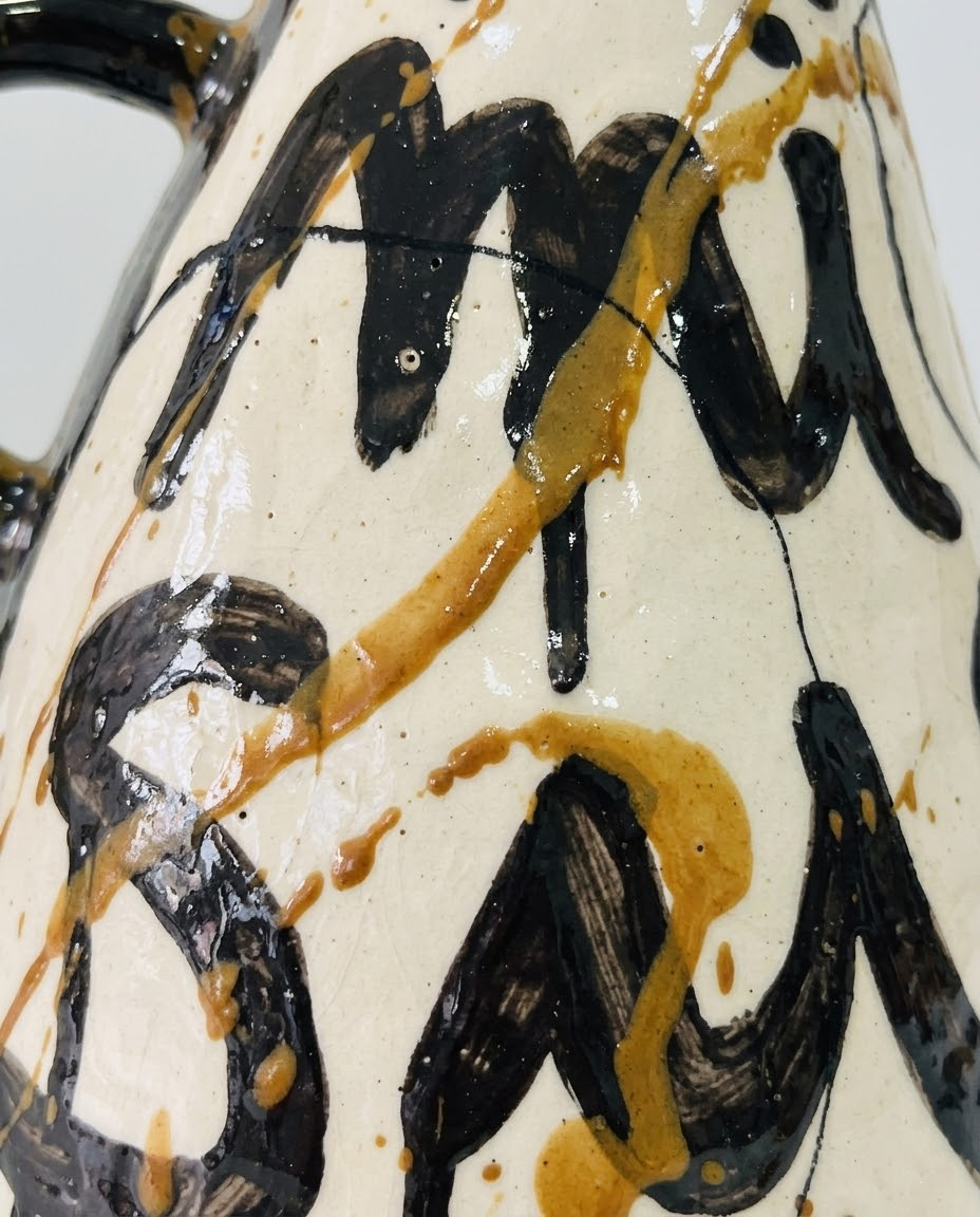 Detalles del Jarrón ATRAPO cerámico de tres asas laterales esmaltadas en negro cobalto, con caligrafía "ATRAPO MI SUERTE" en negro y ocre.
