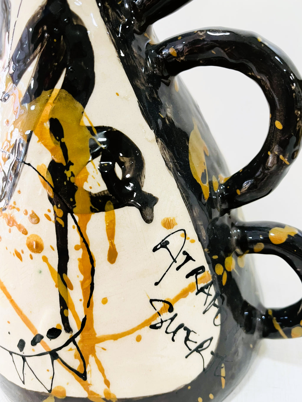 Jarrón ATRAPO cerámico de tres asas laterales esmaltadas en negro cobalto, con caligrafía "ATRAPO MI SUERTE" en negro y ocre, con espigas de trigo secas.