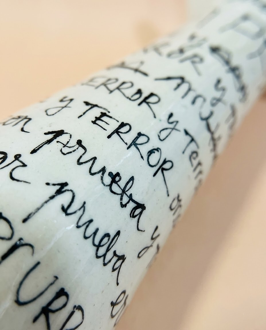 Primer plano de la caligrafía continua en negro cobalto sobre el esmalte blanco roto del Jarrón ERROR de cerámica.