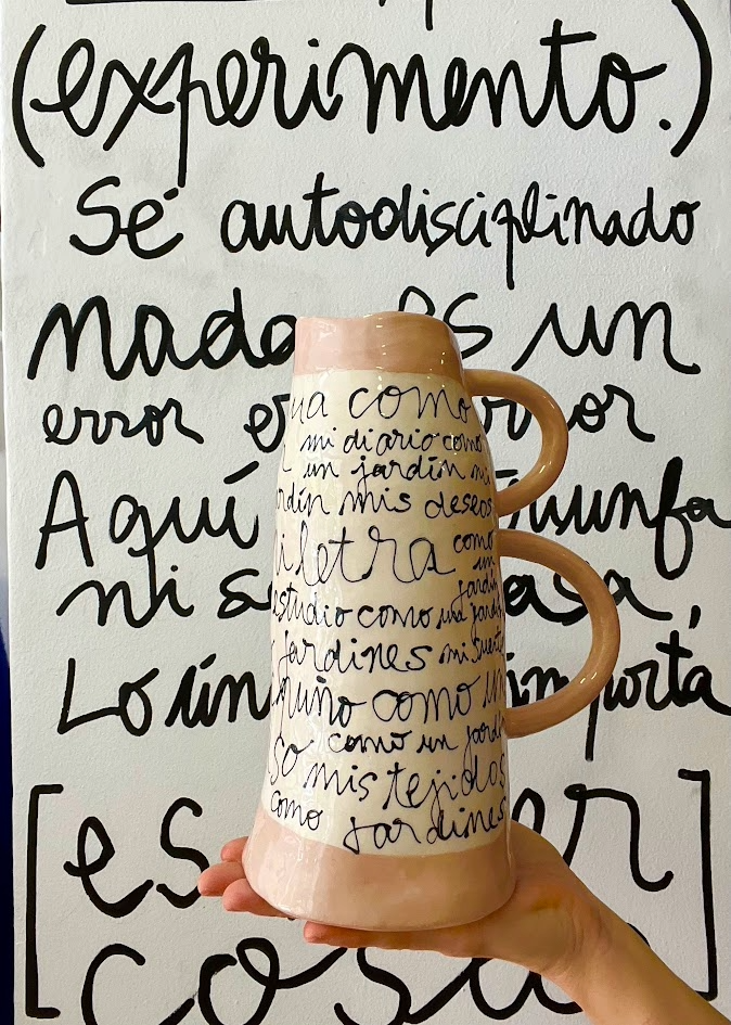 Vista frontal del Jarrón LETRA cerámico de gran formato, mostrando su forma cilíndrica con tres asas y caligrafía expresionista en negro y salmón.