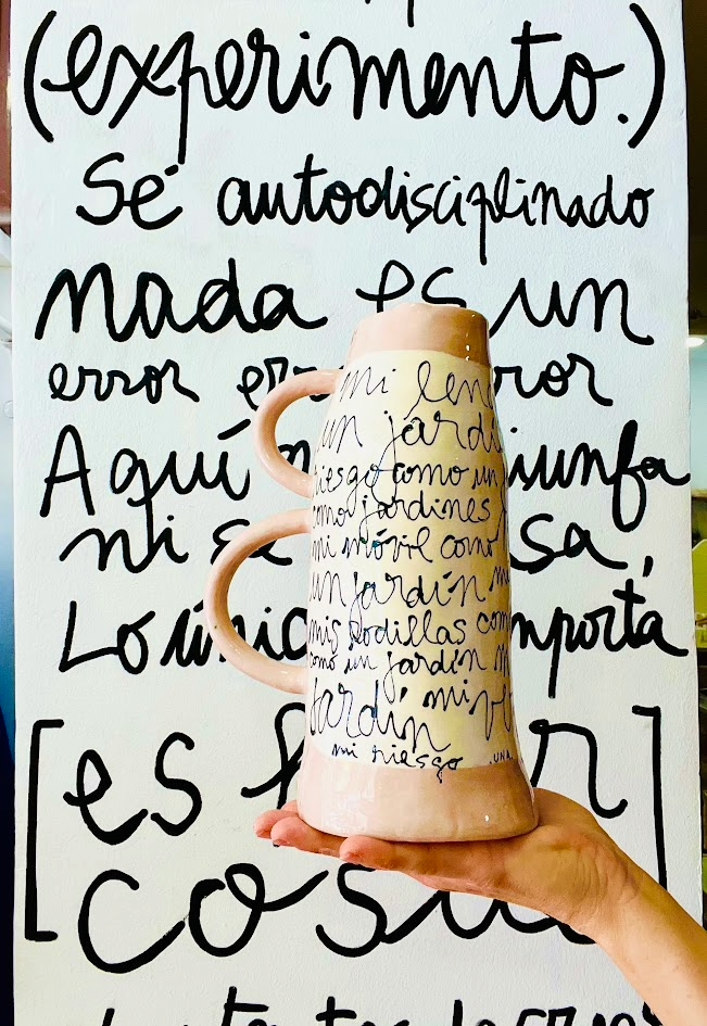Perspectiva del Jarrón LETRA de cerámica, resaltando el bloque de color salmón pastel en el cuello y el trazo caligráfico manual.