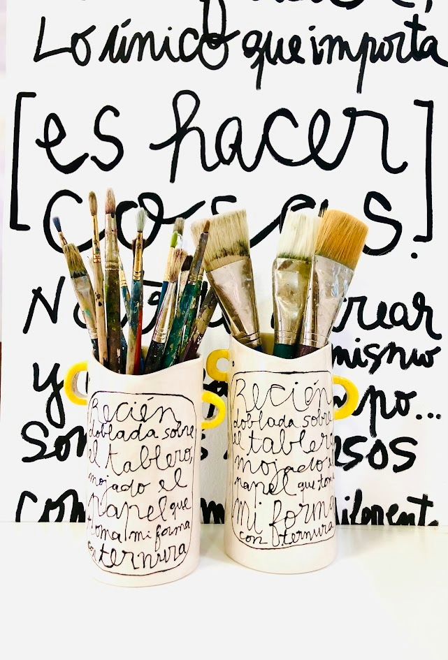 Vista frontal del Jarrón TINTA cerámico con asas amarillo ocre, mostrando su forma cilíndrica con boca ondulada y caligrafía expresionista en negro cobalto.