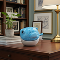 Escultura de pez globo en gres azul de Vicente Rivera, situada en un escritorio de madera frente a una estantería de libros, destacando su textura y acabado brillante en un ambiente de estudio elegante.