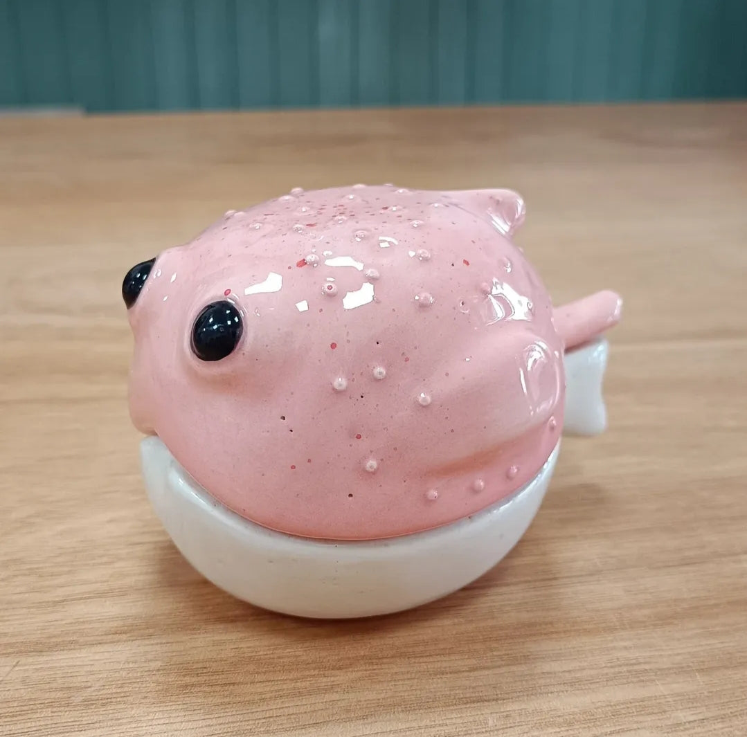 Figura artesanal de pez globo en gres rosa moteado con detalles de textura en relieve, creada a mano por el artista Vicente Rivera.