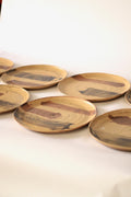 Plato circular de cerámica artesanal de 30 cm con textura rugosa y esmaltado en tonos grisáceos y ocre.